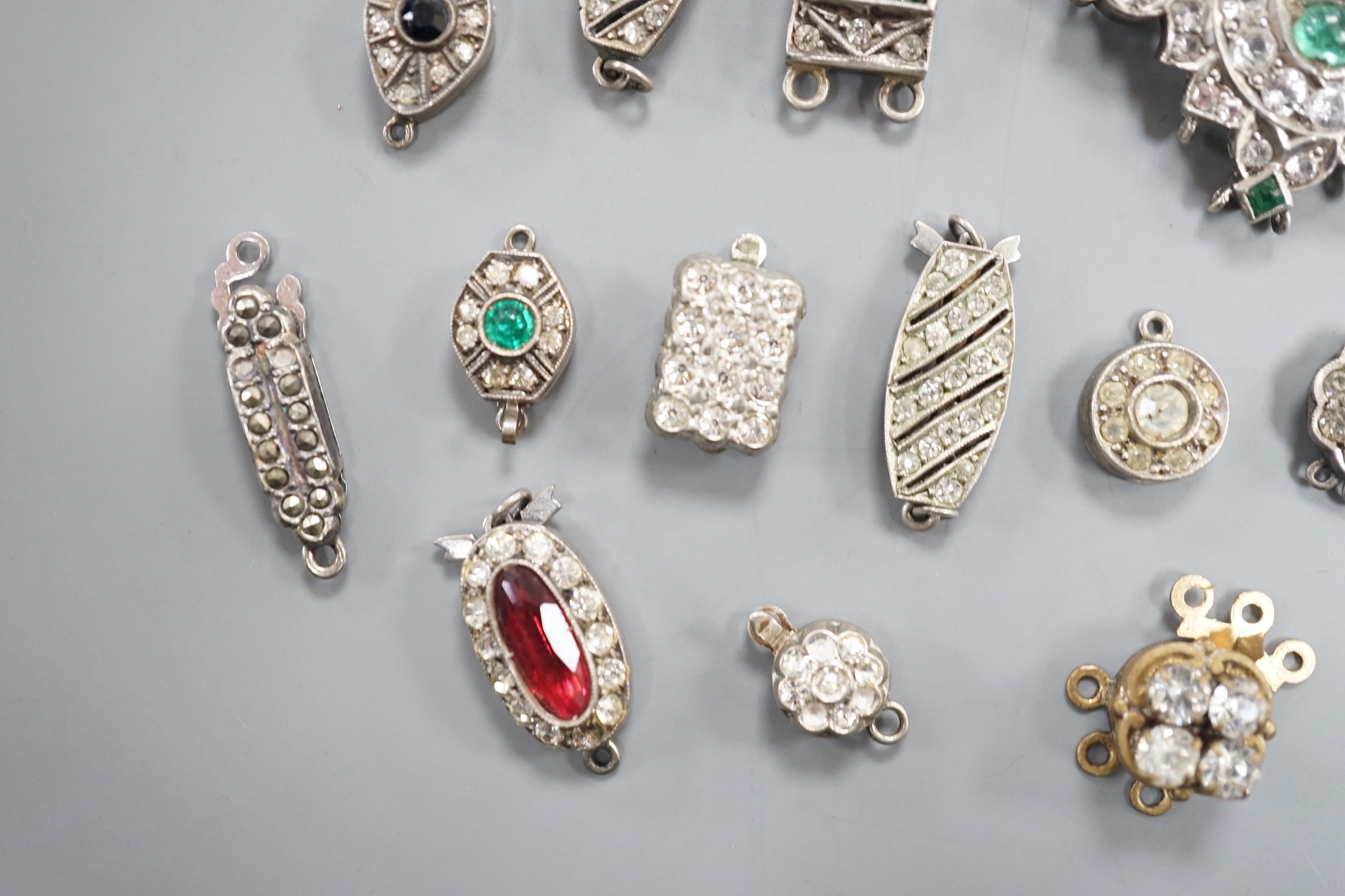 A small group of assorted white or base metal and paste set clasps.